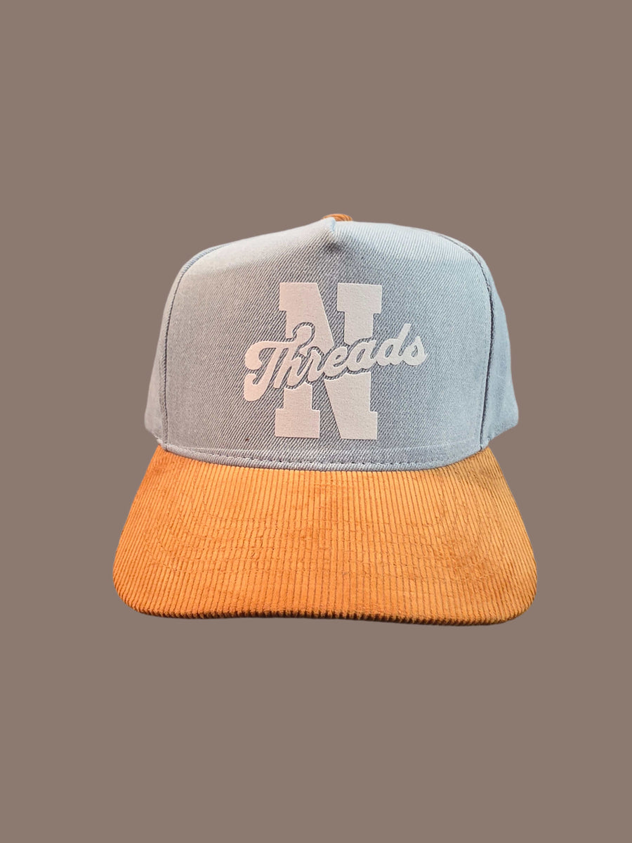 Trucker hat with orange brim and gray mesh back on a brown background

